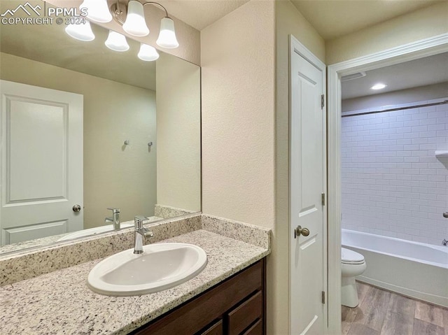 full bathroom with wood-type flooring, vanity, toilet, and tiled shower / bath