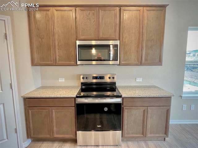 kitchen featuring light stone countertops, stainless steel appliances, and light hardwood / wood-style floors