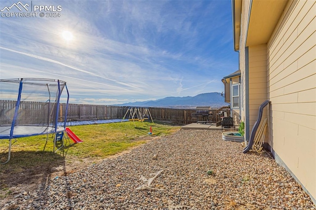 view of yard with a patio area, a mountain view, and a trampoline