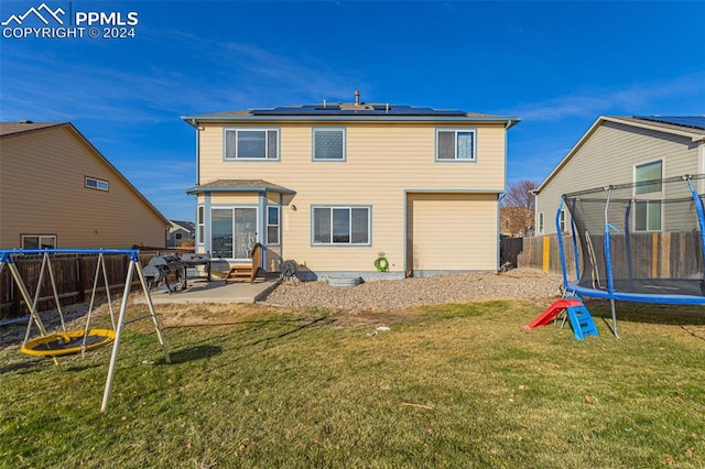 back of house featuring a yard, a patio, and a trampoline