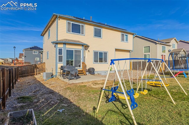 back of house featuring a lawn, a patio area, a playground, and central AC