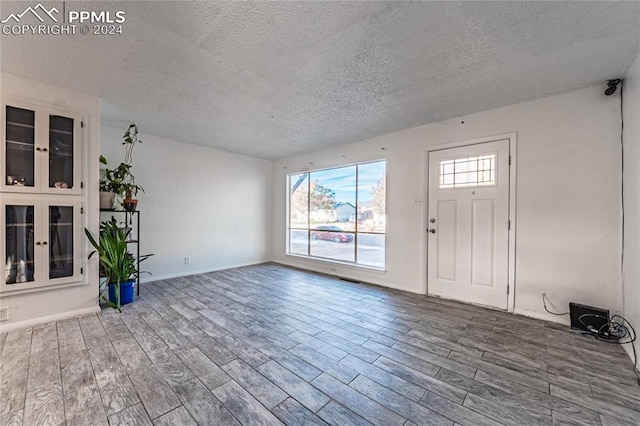 foyer entrance with hardwood / wood-style floors and a textured ceiling