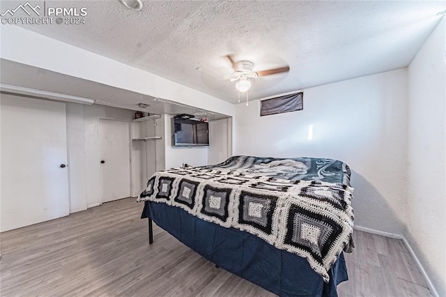 bedroom with a textured ceiling, light hardwood / wood-style flooring, and ceiling fan