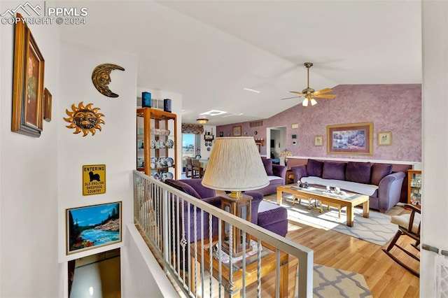 living room with hardwood / wood-style floors, ceiling fan, and vaulted ceiling