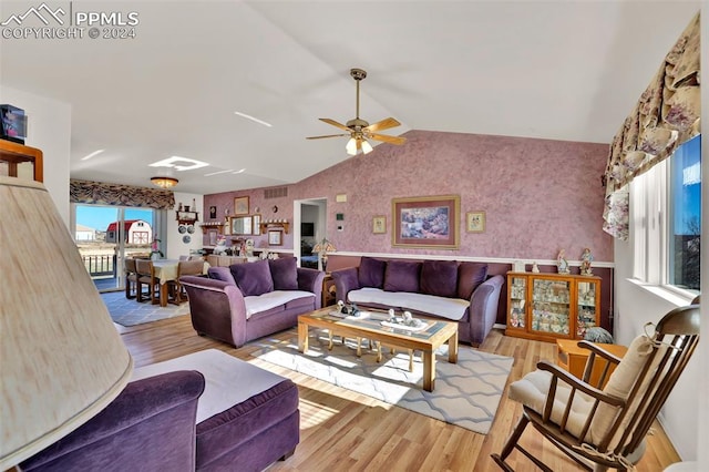 living room with ceiling fan, light hardwood / wood-style floors, and vaulted ceiling