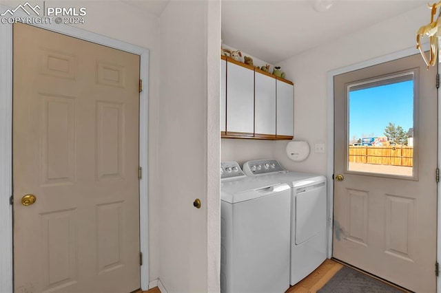 washroom featuring cabinets, washing machine and dryer, and light hardwood / wood-style floors