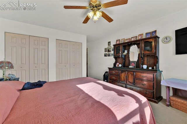 carpeted bedroom with ceiling fan and multiple closets