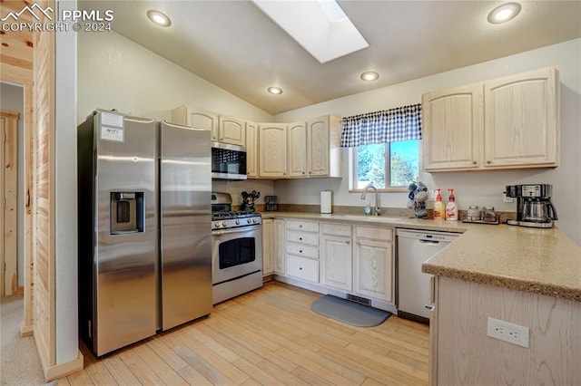 kitchen featuring light wood-type flooring, lofted ceiling with skylight, sink, and appliances with stainless steel finishes