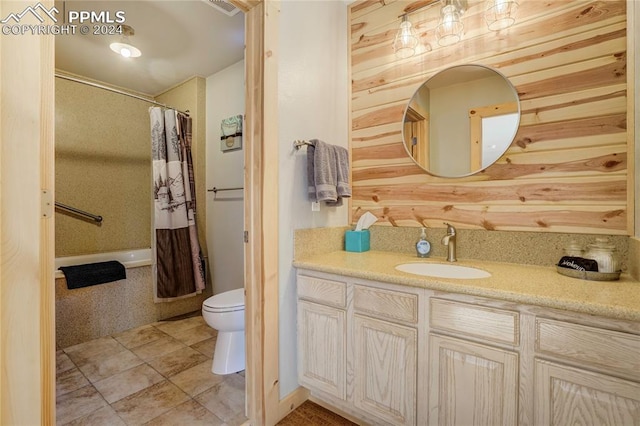 full bathroom with shower / bath combo, vanity, wooden walls, tile patterned flooring, and toilet