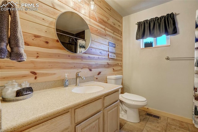 bathroom featuring tile patterned floors, vanity, wood walls, and toilet