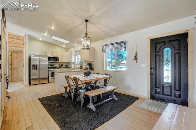 dining room with light hardwood / wood-style flooring, a notable chandelier, lofted ceiling, and sink