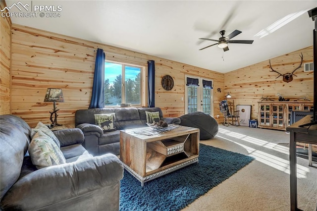 living room with carpet, french doors, wooden walls, vaulted ceiling with skylight, and ceiling fan