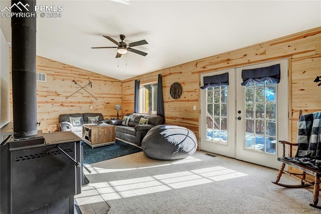 living room featuring a wood stove, french doors, carpet, and vaulted ceiling