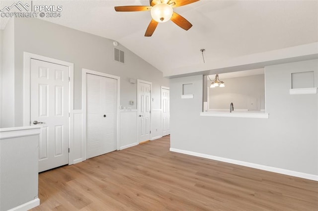 spare room featuring ceiling fan with notable chandelier, lofted ceiling, and light hardwood / wood-style flooring