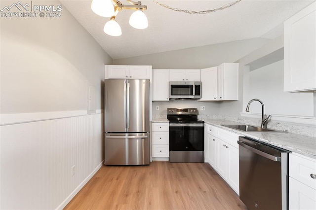 kitchen featuring white cabinetry, sink, stainless steel appliances, light hardwood / wood-style floors, and vaulted ceiling