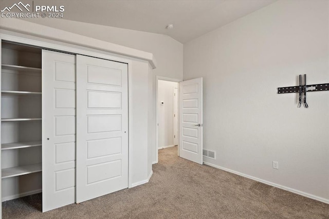 unfurnished bedroom with carpet, vaulted ceiling, and a closet