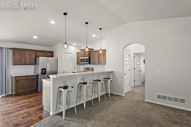 kitchen featuring lofted ceiling, backsplash, a kitchen breakfast bar, appliances with stainless steel finishes, and kitchen peninsula