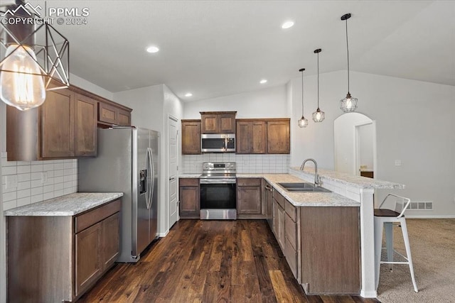 kitchen with kitchen peninsula, stainless steel appliances, decorative light fixtures, a breakfast bar area, and lofted ceiling