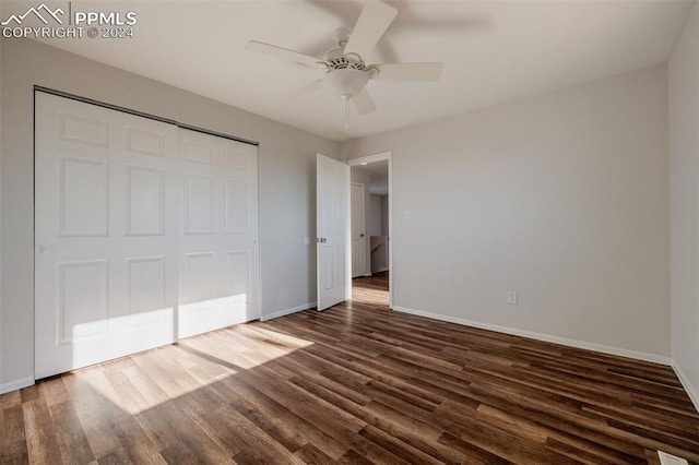 unfurnished bedroom with dark hardwood / wood-style flooring, a closet, and ceiling fan