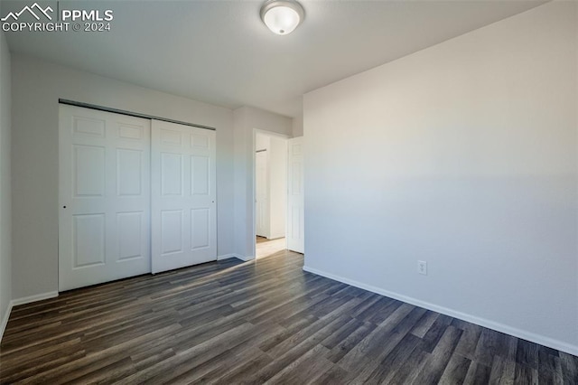 unfurnished bedroom featuring a closet and dark wood-type flooring