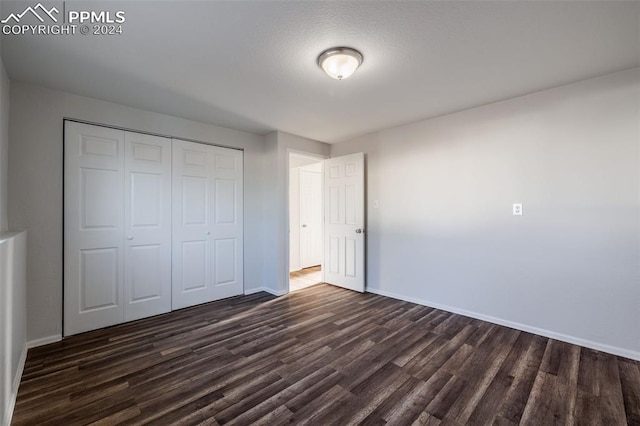 unfurnished bedroom featuring dark hardwood / wood-style floors, a textured ceiling, and a closet