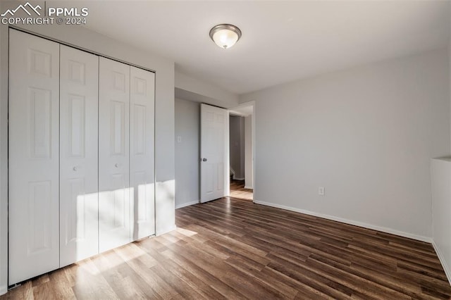 unfurnished bedroom featuring a closet and dark hardwood / wood-style flooring