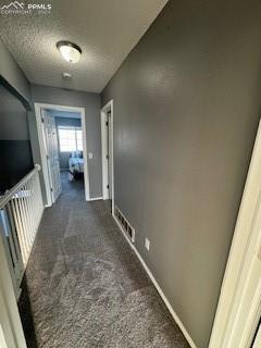 corridor featuring dark carpet and a textured ceiling