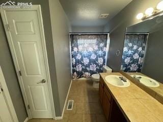 bathroom with toilet, vanity, and tile patterned flooring