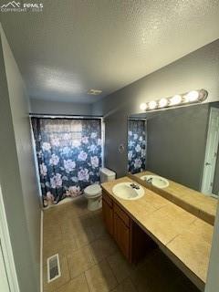 bathroom with toilet, a textured ceiling, and vanity