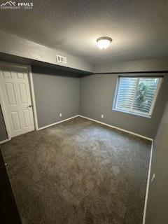 basement with a textured ceiling and dark carpet