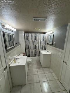 bathroom featuring a textured ceiling, toilet, vanity, and tile patterned flooring