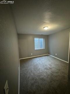 unfurnished room with a textured ceiling and dark colored carpet