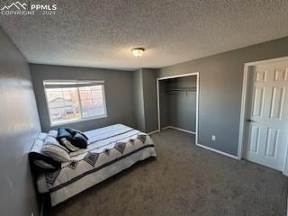 bedroom with a textured ceiling, a closet, and dark colored carpet