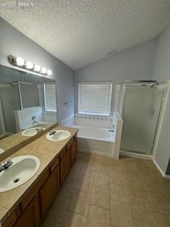 bathroom featuring a textured ceiling, shower with separate bathtub, lofted ceiling, and vanity