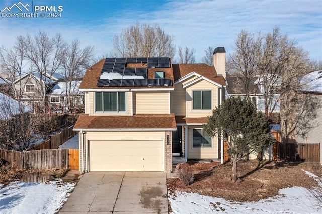 view of property featuring a garage and solar panels