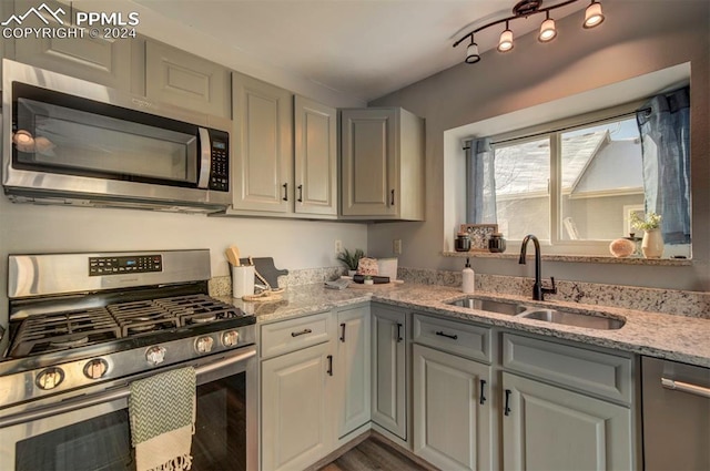 kitchen featuring light stone counters, stainless steel appliances, sink, and gray cabinetry