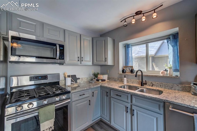 kitchen featuring gray cabinetry, sink, light stone counters, and stainless steel appliances