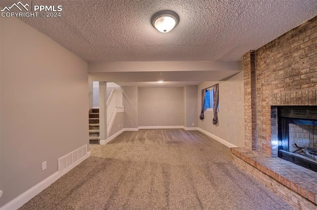 basement with carpet floors, a brick fireplace, and a textured ceiling