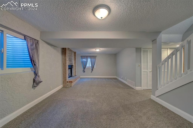 basement featuring carpet flooring, a brick fireplace, and a textured ceiling