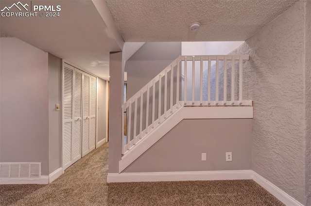 staircase featuring a textured ceiling and carpet