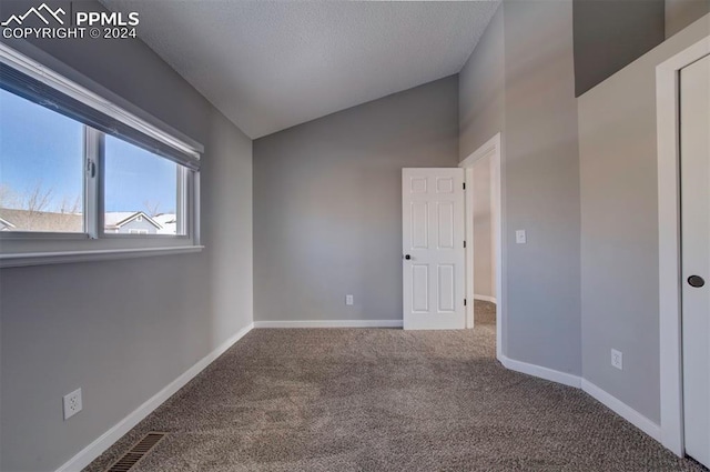 carpeted spare room featuring vaulted ceiling and a textured ceiling