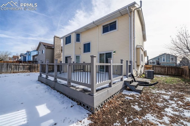 snow covered rear of property featuring cooling unit and a deck