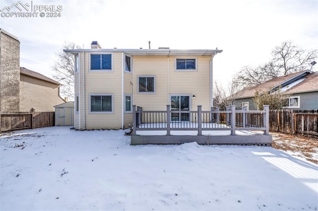 snow covered property with a shed and a deck