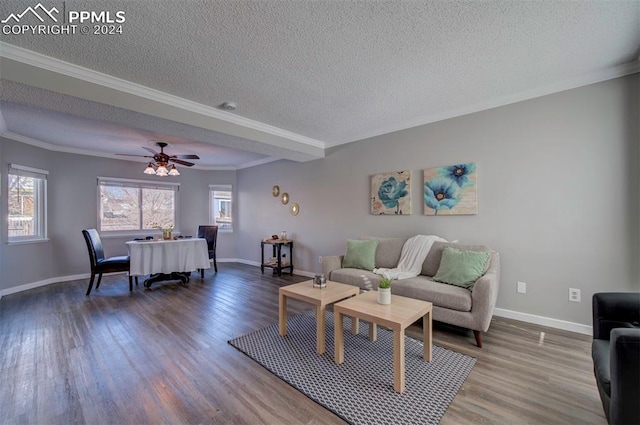 living room with hardwood / wood-style flooring, ceiling fan, ornamental molding, and a textured ceiling