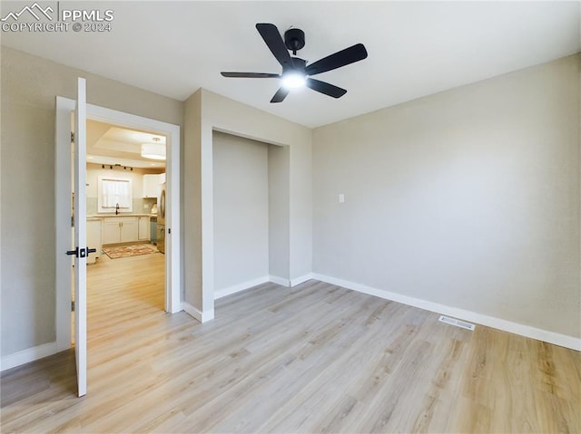 unfurnished bedroom featuring ceiling fan, a closet, light hardwood / wood-style floors, and sink