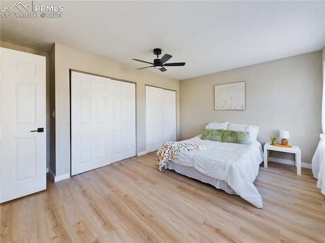 bedroom featuring ceiling fan, light wood-type flooring, and two closets