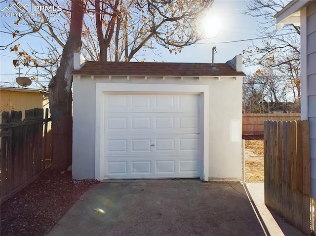 garage with concrete driveway and fence