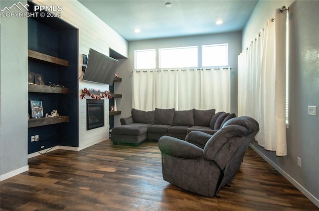 living room featuring built in shelves and dark hardwood / wood-style flooring