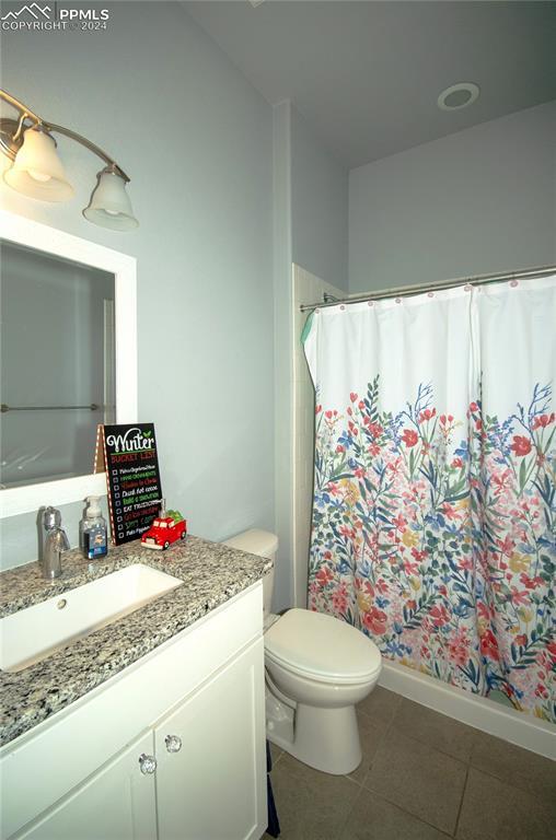 bathroom featuring a shower with curtain, vanity, toilet, and tile patterned floors