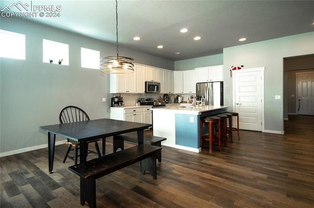 kitchen with white cabinetry, tasteful backsplash, an island with sink, decorative light fixtures, and appliances with stainless steel finishes